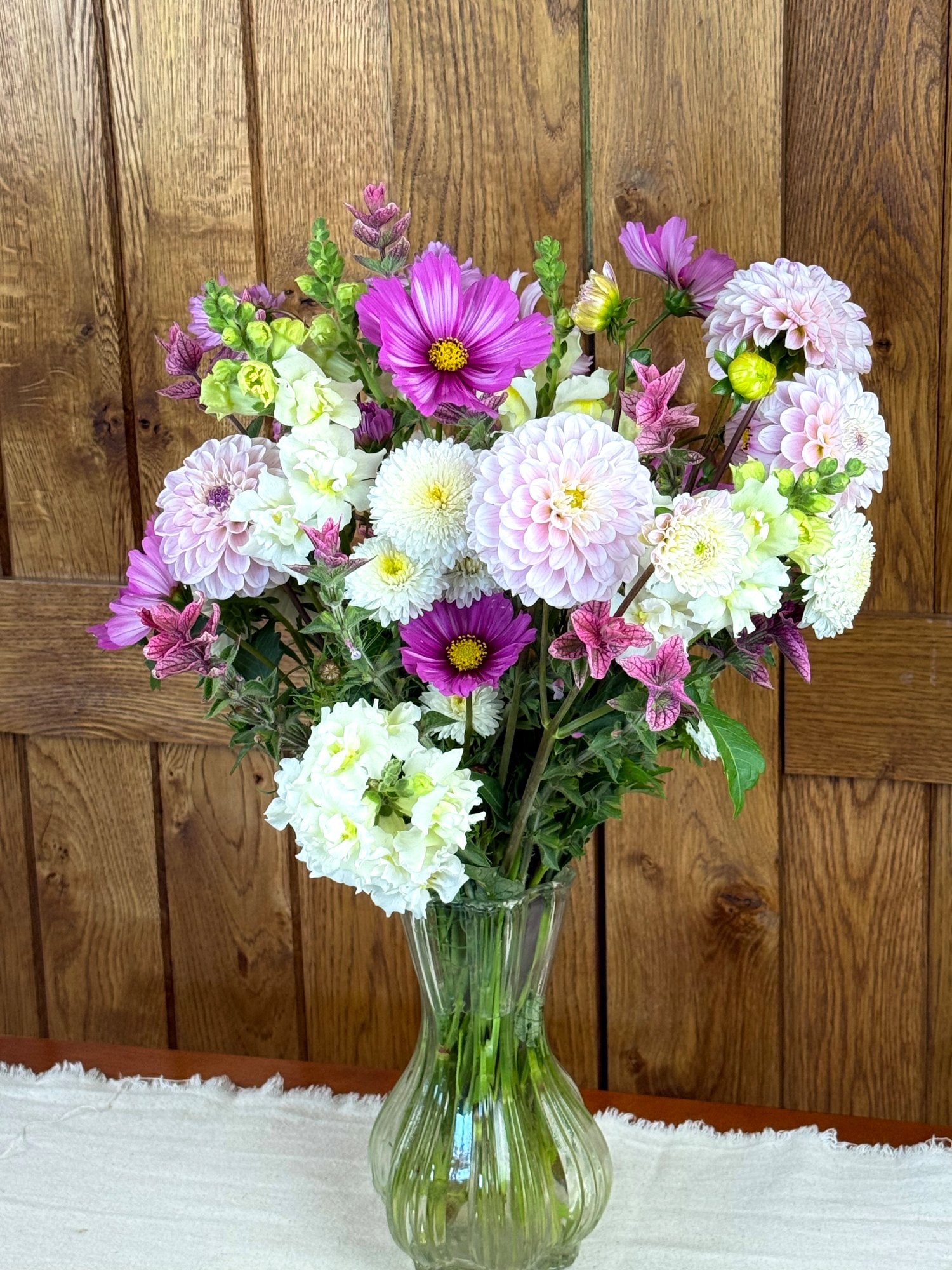 A pink and white market bouquet containing dahlias, cosmos, salvia, and snapdragons.